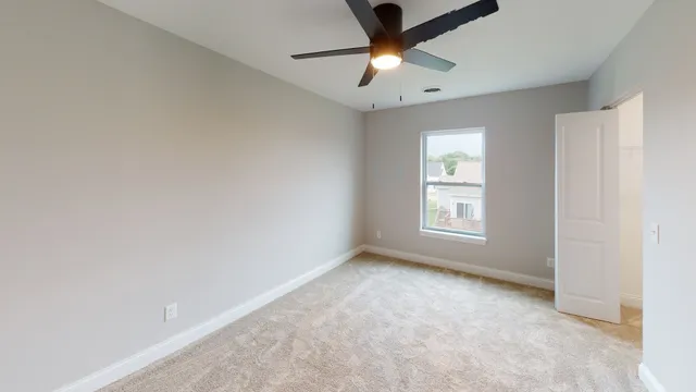 an empty room with a window and a fan