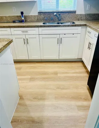 a view of granite countertop white cabinets and wooden floor