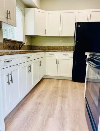 a kitchen with granite countertop a sink a stove and cabinets