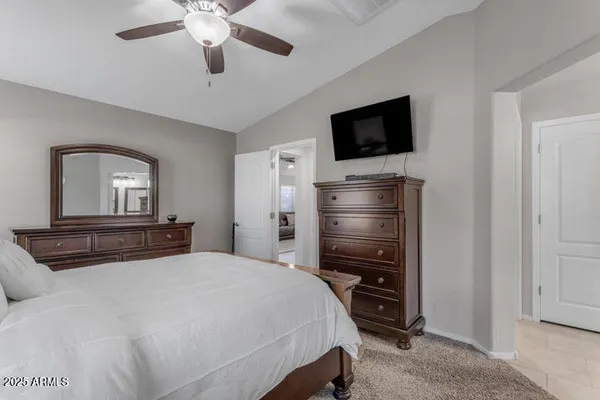 a bedroom with a bed a mirror on dresser and a flat screen tv