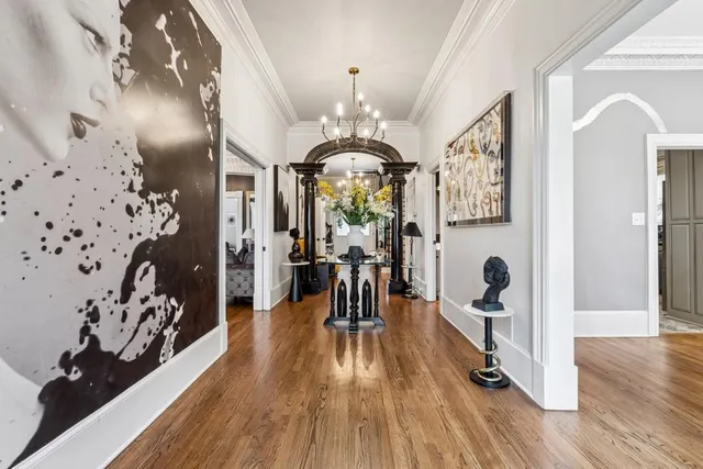 a hallway with a dining table wooden floor and a chandelier