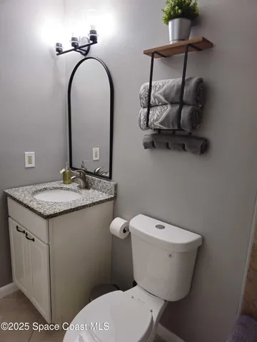 a bathroom with a granite countertop toilet sink and mirror