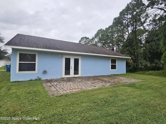 a house that is sitting in the grass with large trees