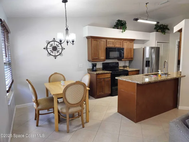 a kitchen with stainless steel appliances granite countertop a sink dishwasher a dining table and chairs with a large mirror