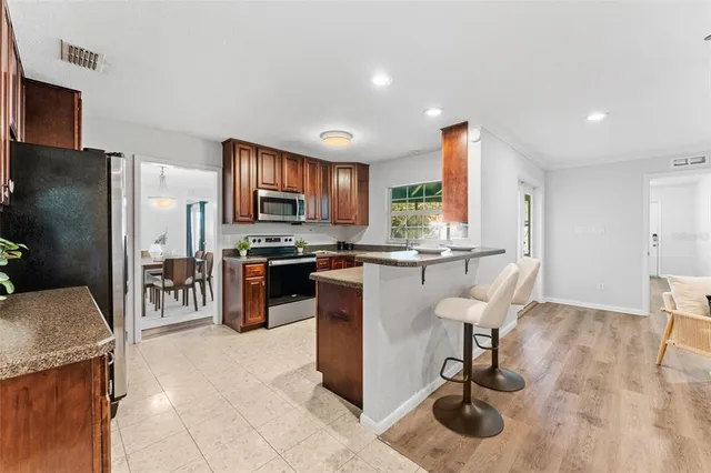 a kitchen with stainless steel appliances granite countertop a refrigerator oven a sink a dining table and chairs