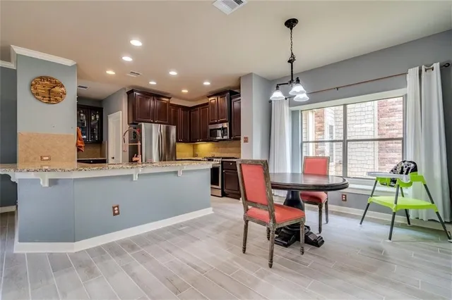 a kitchen with stainless steel appliances kitchen island granite countertop a table chairs and a refrigerator
