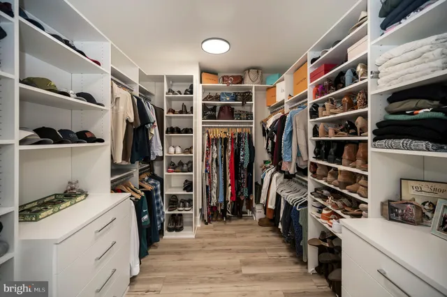 a view of walk in closet with clothes and shoes