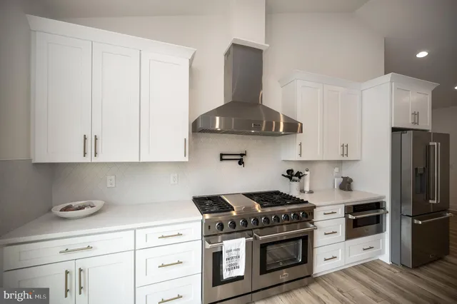 a kitchen with stainless steel appliances granite countertop a stove a refrigerator and a white cabinets