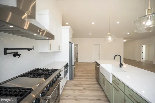 a kitchen with kitchen island stainless steel appliances a sink a stove top oven a counter space and cabinets