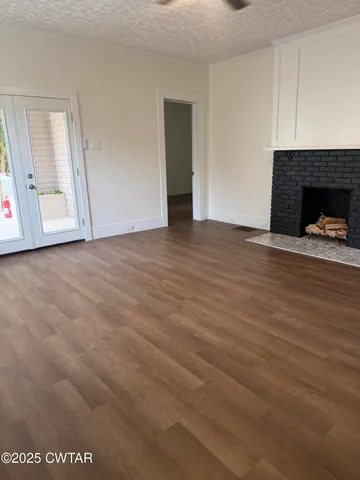 a view of empty room with wooden floor and fireplace