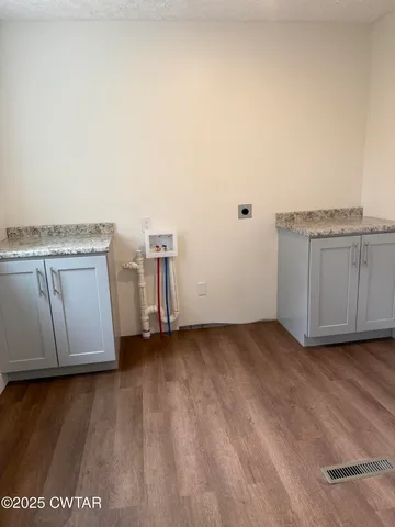 a view of a utility room with cabinets and wooden floor
