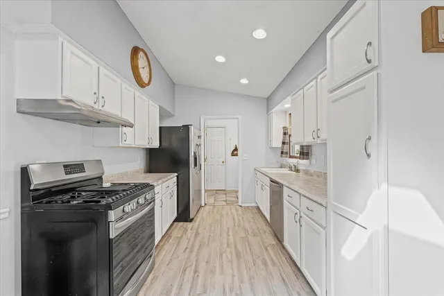 a kitchen with stainless steel appliances granite countertop a refrigerator and white cabinets
