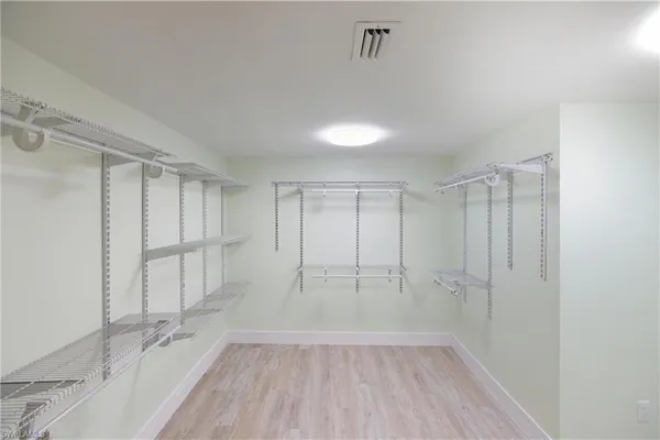 an empty room with wooden floor closet and windows