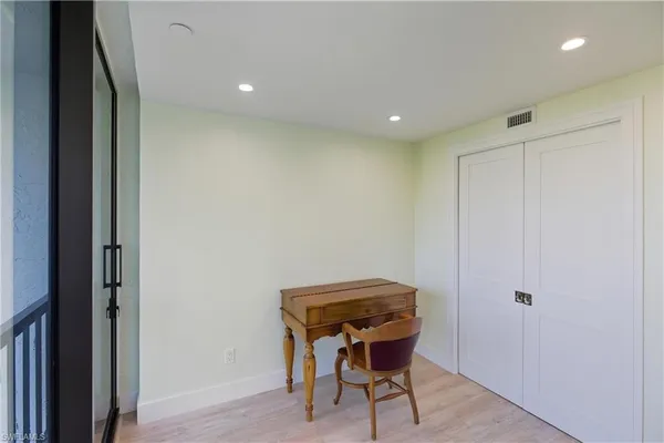 a view of an empty room with wooden floor and a balcony