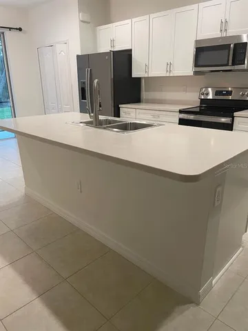 a kitchen with stainless steel appliances a sink a stove a microwave a refrigerator and cabinets