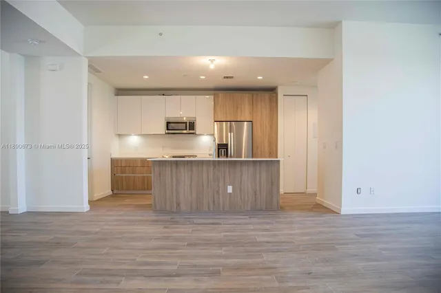 a view of kitchen and empty room with wooden floor