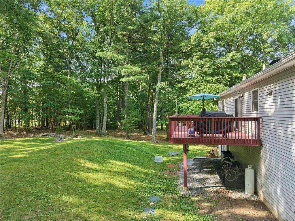 128 Chestnut Street Dingmans Ferry, PA 18328 - Photo 33 of 43 A spacious grassy yard extends to a verdant treeline, featuring a raised outdoor deck for alfresco gatherings.