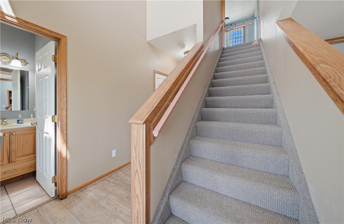 12159 Lawndell Road Southwest Beach City, OH 44608 - Photo 24 of 49 Carpeted staircase with wood handrails, featuring light neutral wall paint and wood-finish flooring at the base