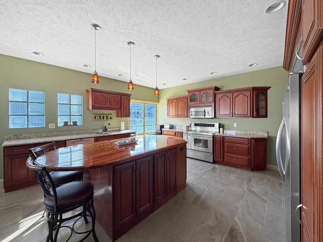 a kitchen with stainless steel appliances kitchen island granite countertop a table chairs and a refrigerator