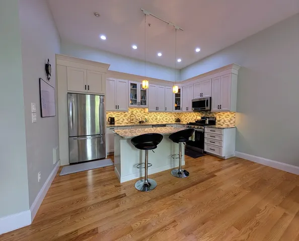 a kitchen with stainless steel appliances kitchen island hardwood floor stove a table and chairs