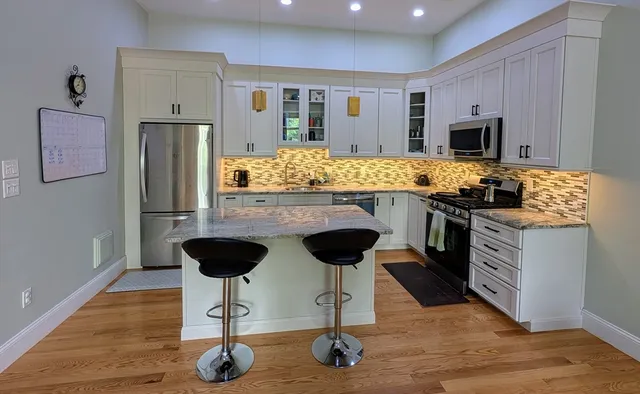 a kitchen with stainless steel appliances granite countertop a stove refrigerator and cabinets