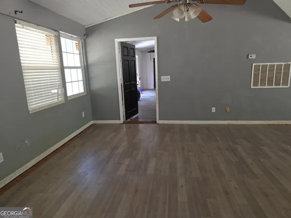an empty room with wooden floor and windows