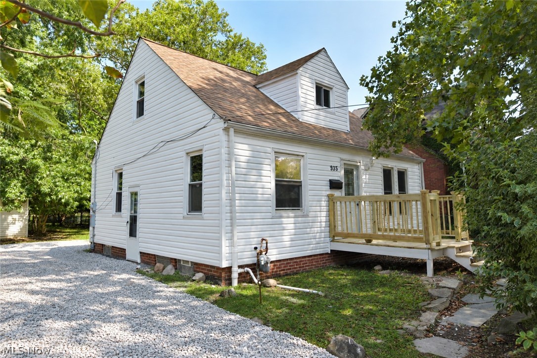 935 Worden Road Wickliffe, OH 44092 - Photo 3 of 30 White siding exterior with a brown shingle roof, featuring a new wooden front deck, a gravel driveway, and a visible side entry