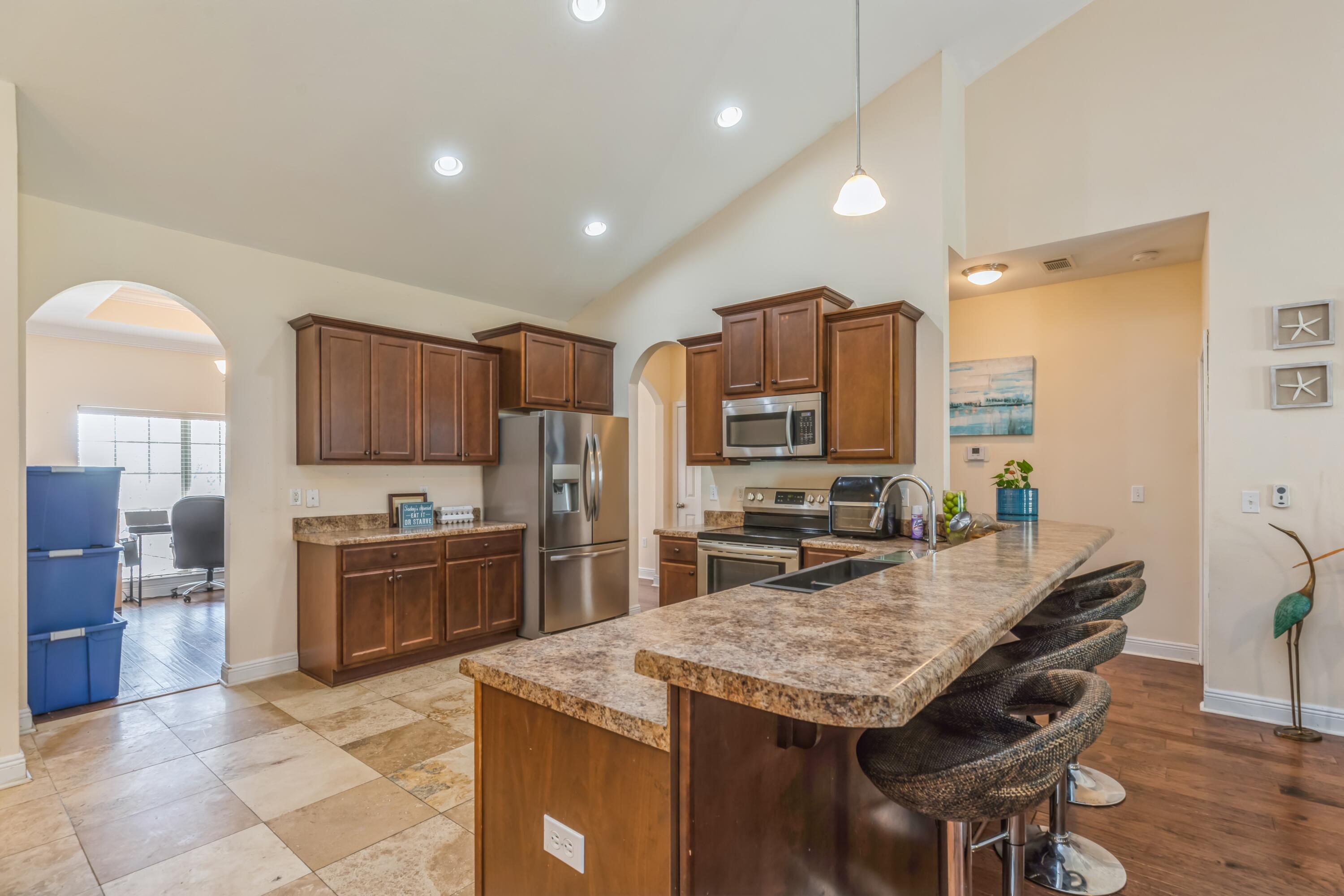 609 Rowan Circle Crestview, FL 32536 - Photo 16 of 37 a kitchen with stainless steel appliances granite countertop a kitchen island hardwood floor sink stove dining table and chairs
