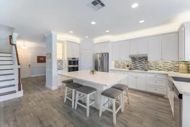 a kitchen with stainless steel appliances kitchen island granite countertop a refrigerator and cabinets