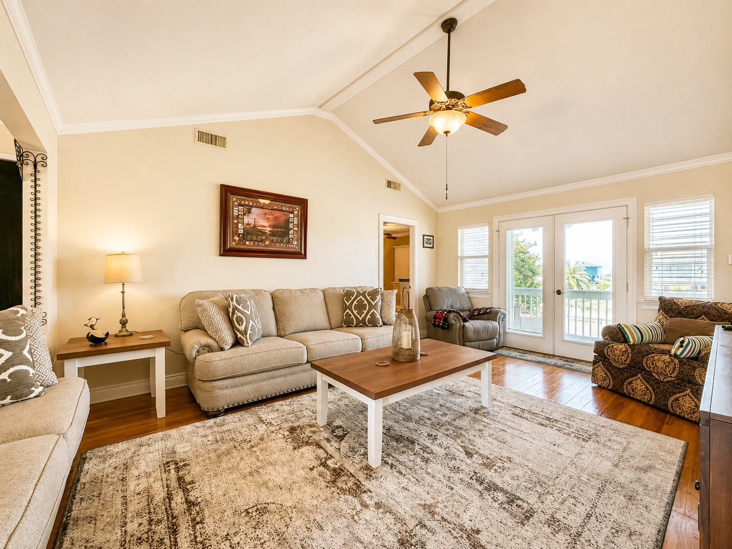 135 Sand Shoals Road Freeport, TX 77541 - Photo 10 of 20 Bright and spacious living room with high ceilings, featuring cozy seating, a ceiling fan, and abundant natural light from large windows and French doors leading to a balcony.