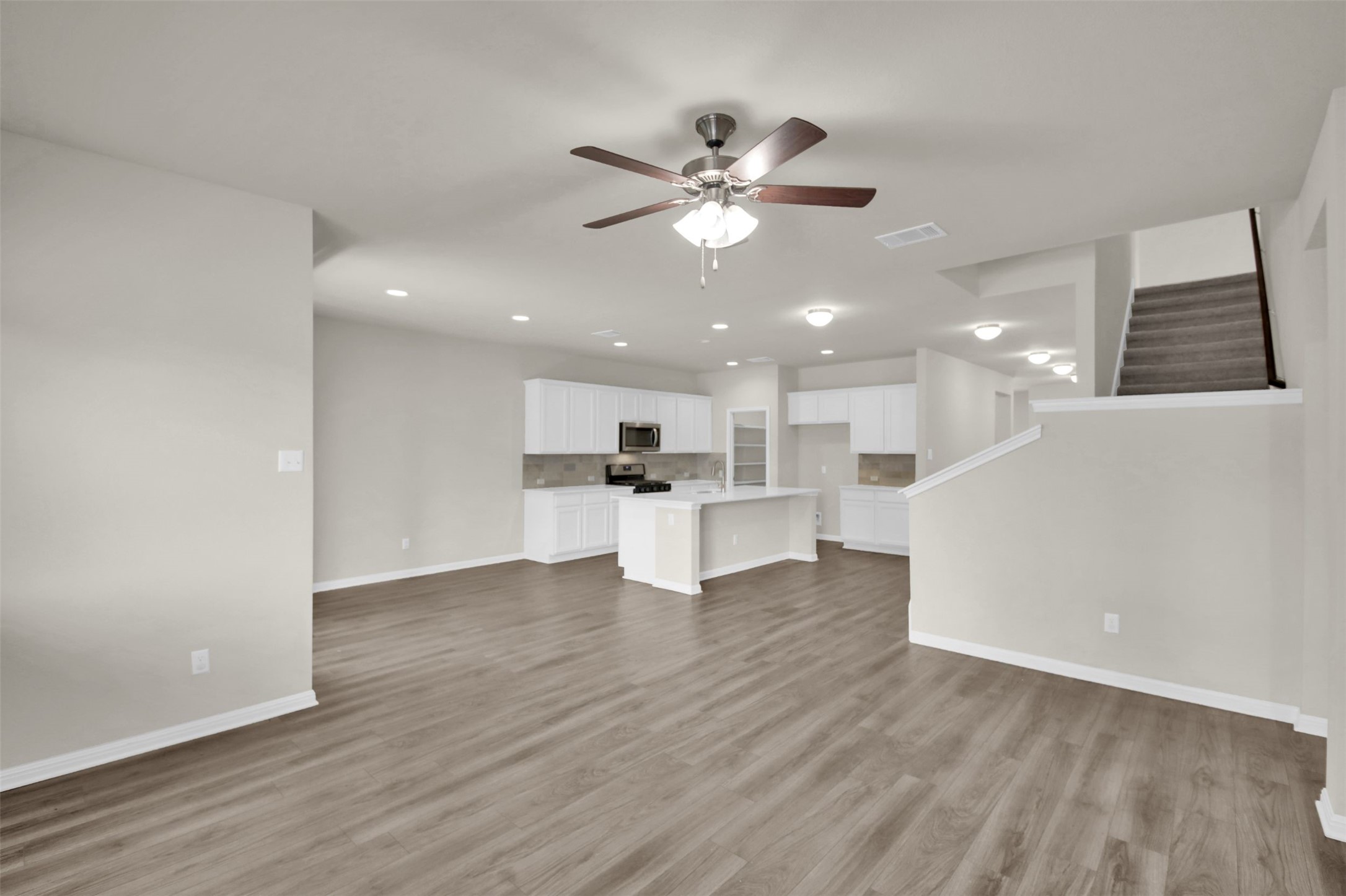 1829 Chickasaw Run Leander, TX 78641 - Photo 18 of 40 a view of an empty room and kitchen with ceiling fan wooden floor and window