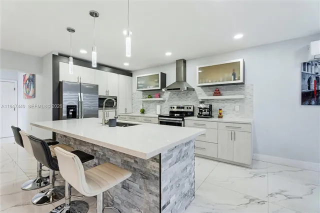 a kitchen with stainless steel appliances kitchen island a table chairs sink and cabinets