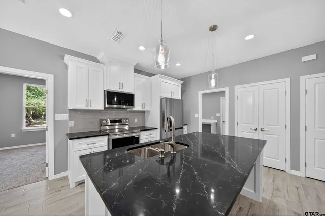 a large kitchen with granite countertop a stove a sink a dining table and chairs