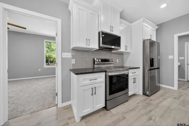 a kitchen with white cabinets stainless steel appliances and a window