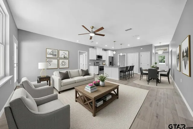 a living room with furniture kitchen view and a wooden floor