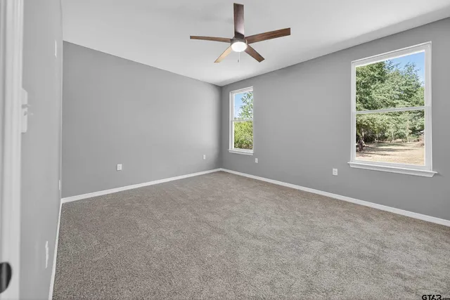 an empty room with windows and ceiling fan