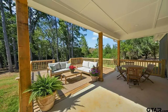 a balcony with wooden floor table and chairs