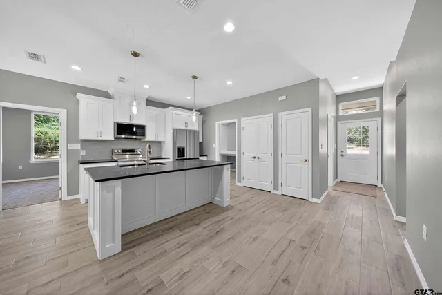 a large kitchen with stainless steel appliances granite countertop a large counter top a sink and a refrigerator