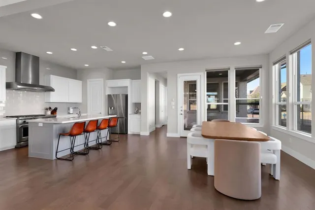 a living room with stainless steel appliances furniture refrigerator and kitchen view