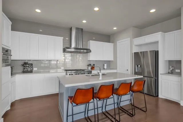 a kitchen with stainless steel appliances granite countertop a sink a stove a refrigerator and cabinets