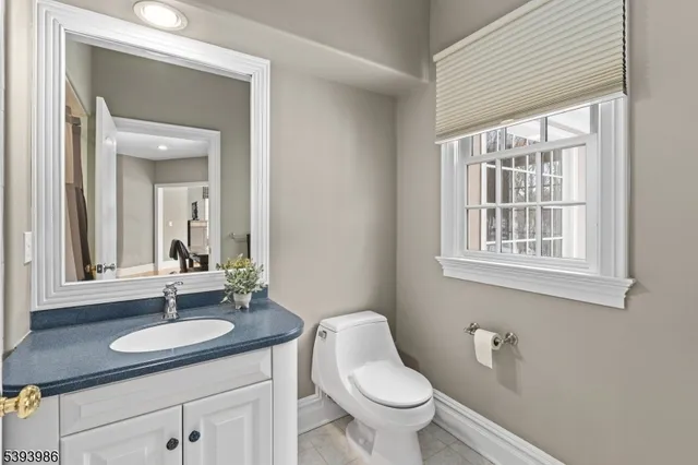 a bathroom with a granite countertop sink toilet a mirror and window