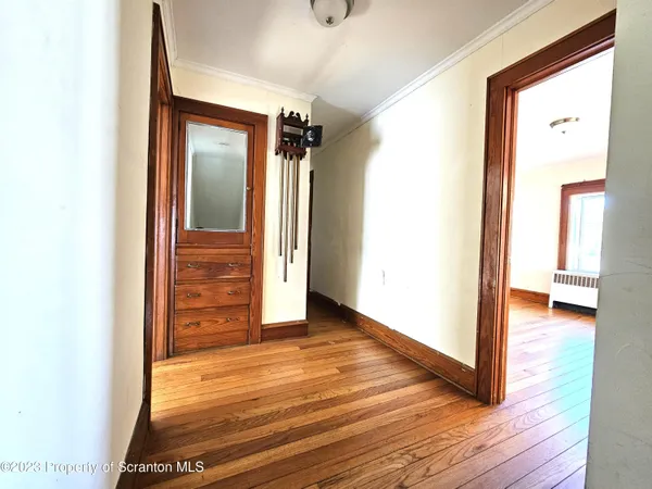 a view of a hallway with wooden floor and a bathroom