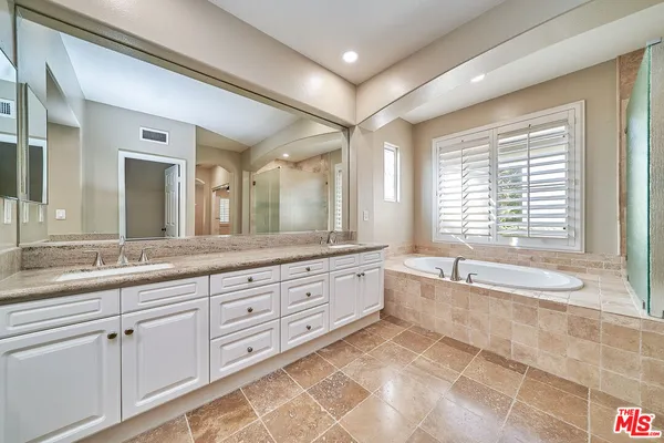 a spacious bathroom with a granite countertop tub sink shower and a large mirror