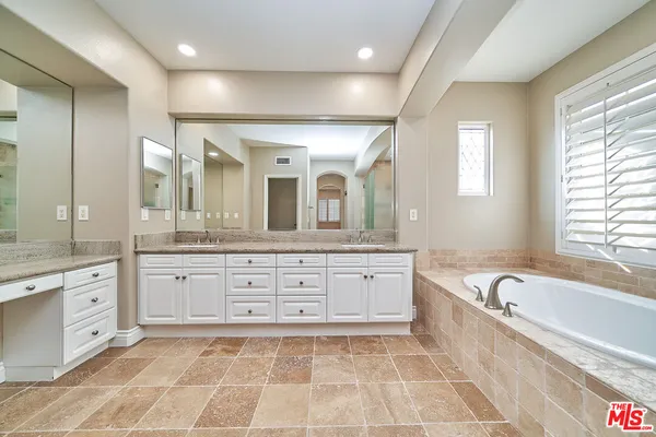 a spacious bathroom with a granite countertop tub sink and mirror