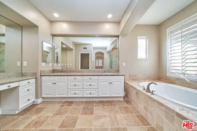 a spacious bathroom with a granite countertop tub sink and mirror