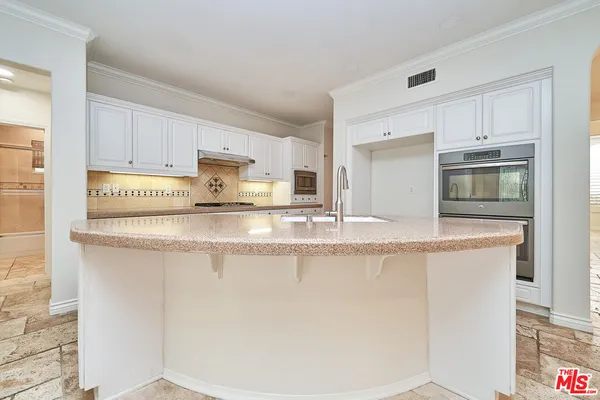 a kitchen with kitchen island granite countertop white cabinets and refrigerator