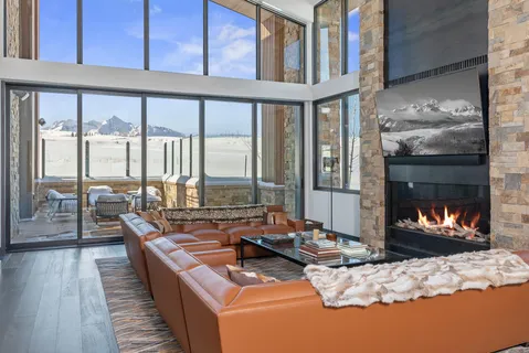 a living room with fireplace furniture large windows and wooden floor
