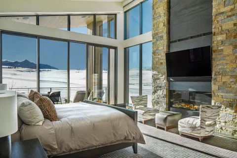 a bedroom with furniture a flat screen tv and a large window