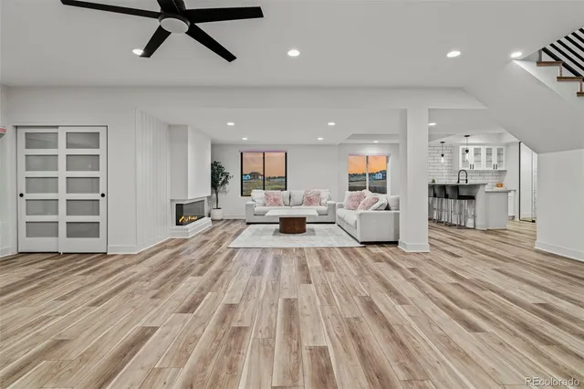a view of a living room with kitchen appliances and a wooden floor
