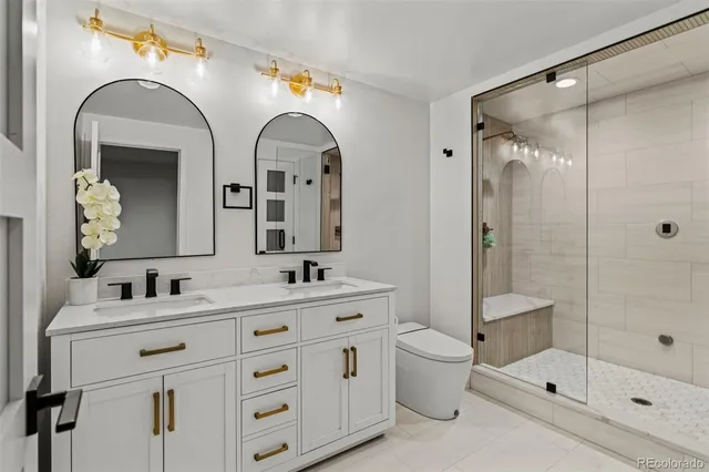 a bathroom with a double vanity sink toilet mirror and shower